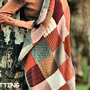 Pode incluir: Padrão de tricô para fazer um cobertor de patchwork. O padrão apresenta uma variedade de cores e texturas, incluindo vermelho, laranja, marrom, cinza e branco. O cobertor é mostrado drapeado sobre uma mulher em pé em uma floresta.