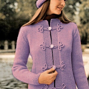 Puede incluir: Patrón de tejido para hacer un abrigo y un gorro. El patrón presenta un abrigo largo de color morado con cierre de botones y un gorro morado a juego.