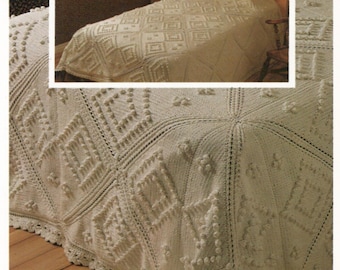 May include: A white crocheted bedspread with a diamond pattern and raised bobbles. The bedspread has a crocheted border.
