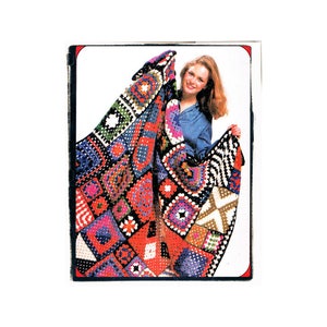 May include: A colorful crocheted blanket with squares of different patterns and colors, including red, blue, green, and white. A person is holding the blanket up in front of them.