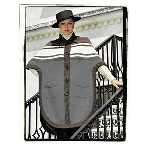 May include: A grey knit poncho featuring a button-down front, two front pockets, and a horizontal striped pattern in white, brown, and dark grey across the upper section. The garment has a dark brown ribbed trim along the edges and collar.