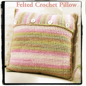 May include: A crocheted pillow with a striped pattern in shades of pink, green, and brown. The pillow has a flap with buttons on the top.