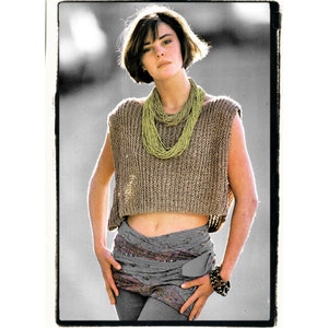May include: A woman wearing a brown knitted sleeveless top with a green beaded necklace, a gray patterned skirt, and a black bracelet.