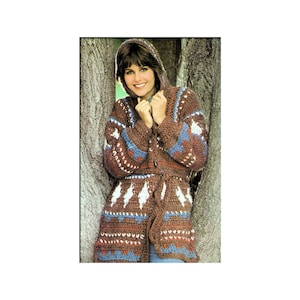 May include: A brown crocheted hooded cardigan with a geometric pattern in white, red, and blue. The cardigan has a tie belt and a front pocket.