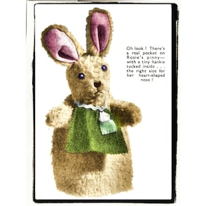 May include: A vintage-style stuffed bunny rabbit with a green apron and a tiny pocket. The bunny has long ears with pink insides and blue eyes. Text on the image reads: "Oh look! There's a real pocket on Rosie's pinny—with a tiny hankie tucked inside."