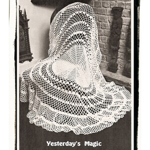 May include: A white crocheted tablecloth with a circular design and a scalloped edge. The tablecloth is draped over a chair in a room with a brick wall. The text "Yesterday's Magic" is printed below the tablecloth.