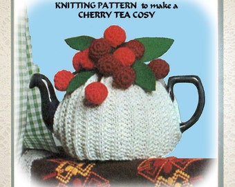 May include: Knitting pattern to make a cherry tea cozy. The cozy is white and has a red cherry design. The cozy is on a teapot.