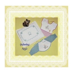 May include: A set of three embroidered baby items, including a pillow, a bib, and a onesie. The pillow is white with blue embroidery of flowers and a wreath. The bib is pink with white embroidery of a bunny. The onesie is green and white gingham with white embroidery of a bunny. The items are displayed on a yellow background with the text "Yesterdays Magic".