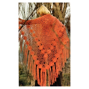 May include: A bright orange crochet shawl with a lacy pattern and fringe. The shawl is draped over a person's shoulders.