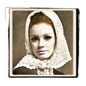 May include: A woman with red hair wears a white crocheted lace shawl over her head. She has a light complexion and is wearing purple lipstick.