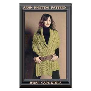 May include: A green knitted wrap cape-stole with a cable knit pattern and a brown leather belt. The caption reads "Aran Knitting Pattern Wrap Cape-Stole".