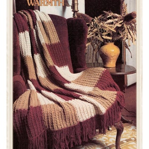 May include: Crochet pattern for a "Beautiful Warmth" Afghan blanket. The blanket is made with a combination of burgundy, beige, and white yarn and has a fringe border.