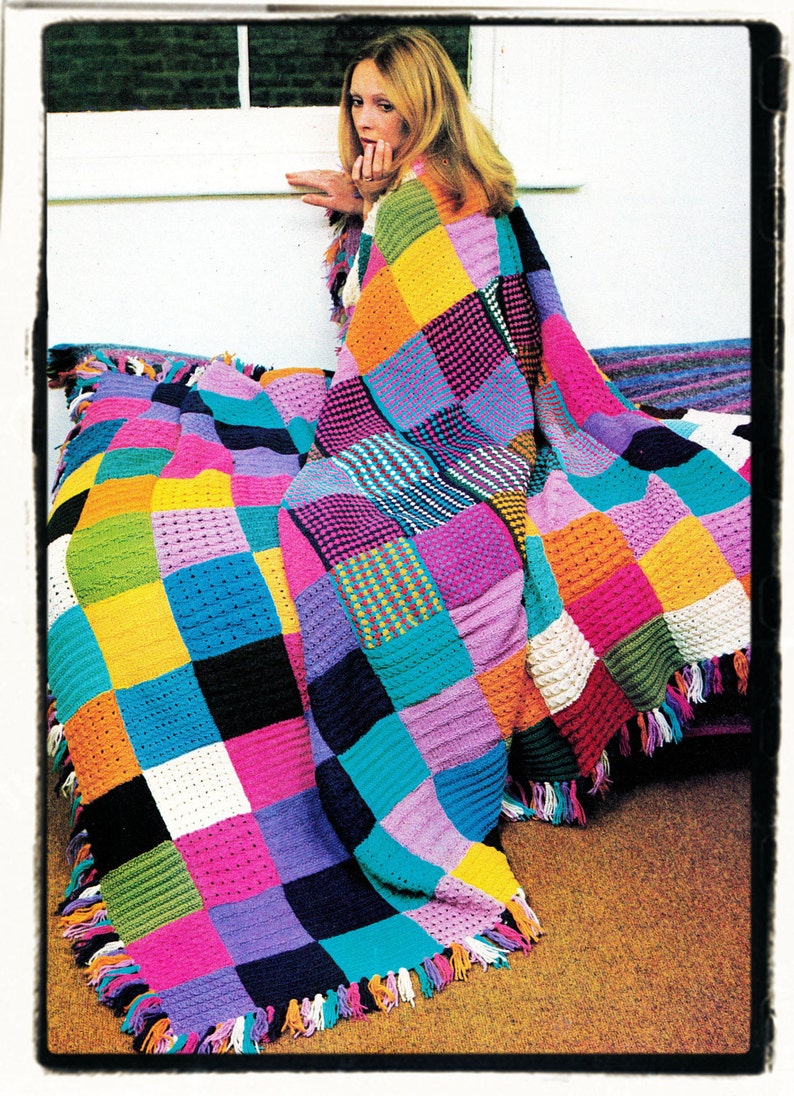 May include: A colorful crocheted blanket with fringe, featuring a patchwork design of squares in various colors, including pink, blue, green, yellow, orange, and purple.