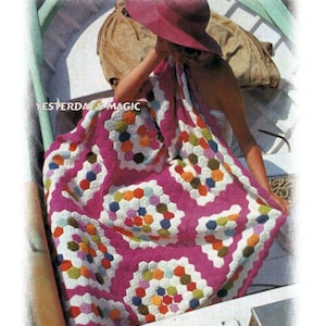 Peut inclure: Une couverture au crochet avec un fond rose et des motifs hexagonaux colorés. La couverture est drapé sur une femme assise dans un bateau. Le texte "Yesterday's Magic" et "Wendy's Vintage Patterns" sont visibles sur l'image.