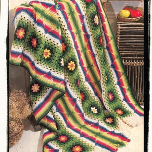 May include: A colorful crocheted blanket with a floral pattern and fringe. The blanket is folded and draped over a chair.