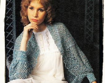 May include: A woman wearing a light blue crocheted shrug over a white dress. The shrug has a lacy pattern and is open in the front.