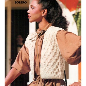 May include: Knitting pattern to make a bolero from Yesterday's Magic. The pattern features a woman wearing a white crocheted bolero vest over a brown shirt.