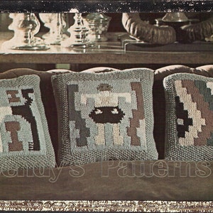 May include: Three knitted throw pillows with geometric patterns in shades of brown, green, and white. The pillows are arranged on a brown leather couch.