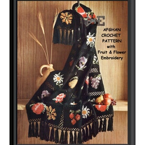 Könnte beinhalten: Schwarze Häkeldecke mit Fransenbordüre und gestickten Früchten und Blumen. Die Decke ist über ein Regal mit einer Kanne und Früchten darauf gelegt. Der Text "Afghan Crochet Pattern with Fruit & Flower Embroidery" ist auf dem Bild gedruckt.