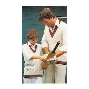 May include: Two people wearing white cable knit vests with red and green trim. The vests have a V-neck and are worn over white shirts. The people are holding a wooden cricket bat.