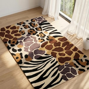 Op de afbeelding: Rechthoekig vloerkleed met dierenprint. Het kleed heeft patronen van luipaardvlekken, zebra strepen en giraffevlekken in bruin, beige en zwart. Het kleed ligt op een lichte houten vloer en geeft een wilde uitstraling.