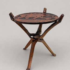 May include: A handcrafted wooden side table with a round top featuring an engraved animal design. The table has three legs and a dark brown finish, showcasing a rustic aesthetic. The table is approximately 46 cm tall.