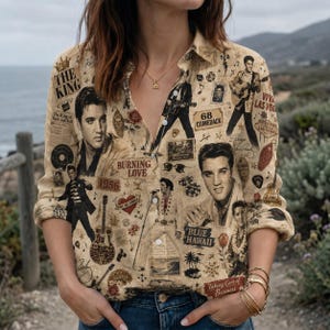 May include: A beige button-down shirt featuring a collage print of Elvis Presley, guitars, roses, and text including The King, 68 Comeback, Burning Love, and Blue Hawaii. The shirt has long sleeves, a collar, and a front button closure.
