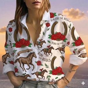 May include: A white long-sleeve button-down shirt featuring a repeating pattern of brown horses, red roses, and brown horseshoes. The text "RUN FOR THE ROSES" is printed in black throughout the design. The shirt has a classic collar and cuffs.