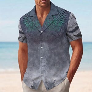 May include: A short-sleeved button-down shirt featuring a realistic print of gray pigeon feathers with iridescent green and teal accents around the collar and shoulders. The shirt has a notched lapel collar and a straight hemline with white buttons.
