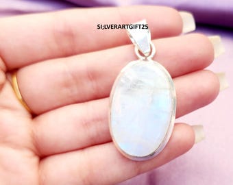 May include: Oval-shaped pendant with a large, iridescent, white gemstone set in a silver metal frame. The pendant is held in a hand with a gold ring. The text "SI;LVERARTGIFT25" is visible.