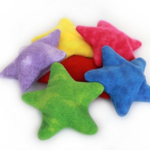 May include: Five plush star-shaped toys in different colors: purple, yellow, red, blue, and green. The stars are arranged in a pile on a white background.