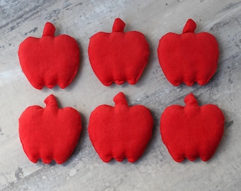 May include: Six red felt apple-shaped pillows. The pillows are arranged in two rows of three.