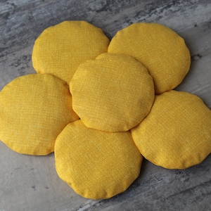 May include: A yellow flower-shaped cushion made of fabric with a textured surface.