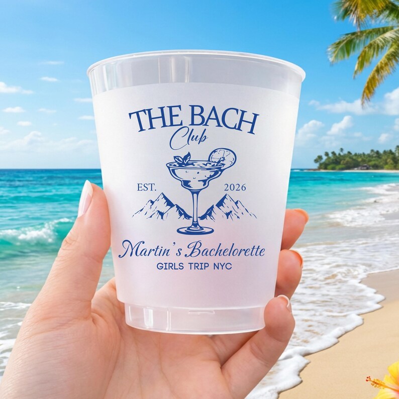 Puede incluir: Un vaso de pl&aacute;stico transl&uacute;cido con texto y gr&aacute;ficos en azul. El dise&ntilde;o incluye las palabras THE BACH CLUB, EST. 2026, Martin's Bachelorette y GIRLS TRIP NYC, centradas alrededor de una ilustraci&oacute;n de una copa de c&oacute;ctel y monta&ntilde;as.