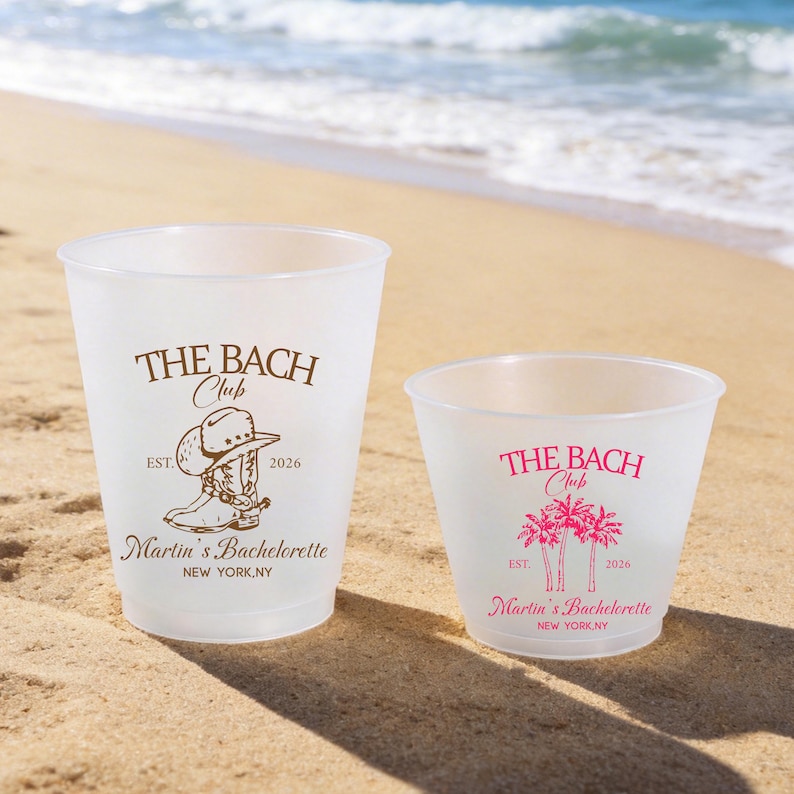 May include: Two frosted plastic cups of different sizes. The larger cup features brown text reading THE BACH CLUB, EST. 2026, Martin's Bachelorette, NEW YORK, NY, and a cowboy boot graphic. The smaller cup has pink text and palm tree graphics.