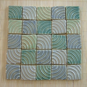 May include: A set of 16 ceramic tiles with a blue, green, and white swirl pattern. The tiles are arranged in a square grid.
