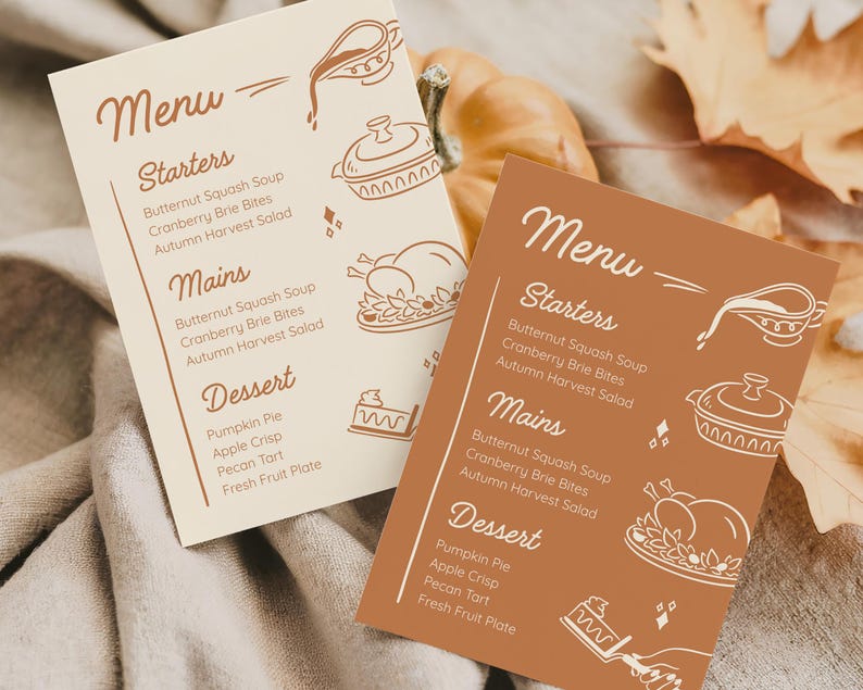 May include: Two menu cards with a fall theme. One card is beige, the other is brown. Both cards have the word "Menu" at the top, followed by "Starters", "Mains", and "Dessert". The menu items are listed below each heading. Decorative illustrations of food are also present.