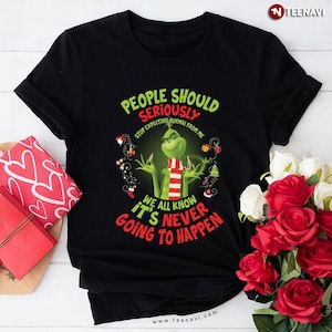Pode incluir: Camiseta preta com um desenho do Grinch. O Grinch está usando um cachecol listrado vermelho e branco. O texto na camiseta diz: "People Should Seriously Stop Expecting Normal From Me. We All Know It's Never Going To Happen."