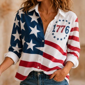 Puede incluir: Una camisa blanca con botones y un diseño patriótico. El lado izquierdo presenta un campo azul con estrellas blancas, mientras que el lado derecho tiene rayas rojas y blancas. El número "1776" está impreso en el pecho.