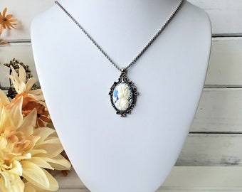 May include: A silver chain necklace with a blue and white cameo pendant. The cameo features a woman's profile in white against a blue background.