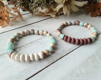 May include: Two beaded bracelets with a mix of light blue, white, and brown beads. One bracelet has a row of brown lava rock beads.