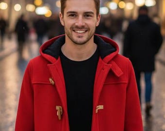 May include: A person wearing a bright red duffel coat with wooden toggles, black shirt, and black pants, standing on a cobblestone street. The background features a blurred street scene with festive lights.