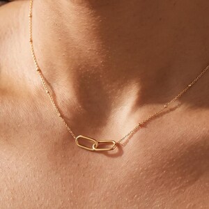 Colar de elos duplos banhado a ouro 18K, pingente oval entrelaçado, corrente delicada e minimalista, joia moderna para sobreposição, estilo para o dia a dia.