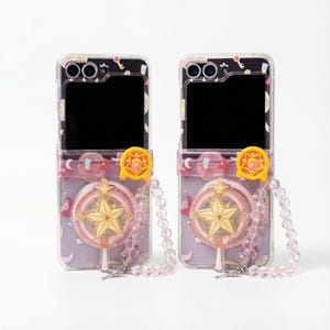 Puede incluir: Dos fundas transparentes para teléfono con una sección superior negra y una sección inferior de color lila claro. Cada funda presenta un diseño en forma de estrella con un cierre amarillo y una correa de cuentas. Las fundas están diseñadas para sostener un teléfono.