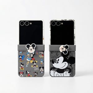 Pode incluir: Duas capas de telemóvel com um design de bolso cinzento com Mickey Mouse. Uma capa tem uma colagem de personagens do Mickey Mouse, e a outra uma ilustração a preto e branco do Mickey Mouse. Cada capa tem um berloque de cabeça do Mickey Mouse.