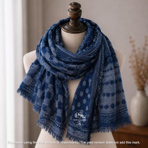 May include: A blue scarf featuring a mix of patterns including checkered squares, polka dots, and geometric shapes. The scarf has a frayed edge finish and displays a circular logo with the text Softwrapgifts printed on the lower section.