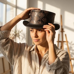 May include: A black top hat with a skull and floral pattern in brown. The hat has a wide brim and a tall crown. The hat is being held up by a person. The hat is a fashion accessory.