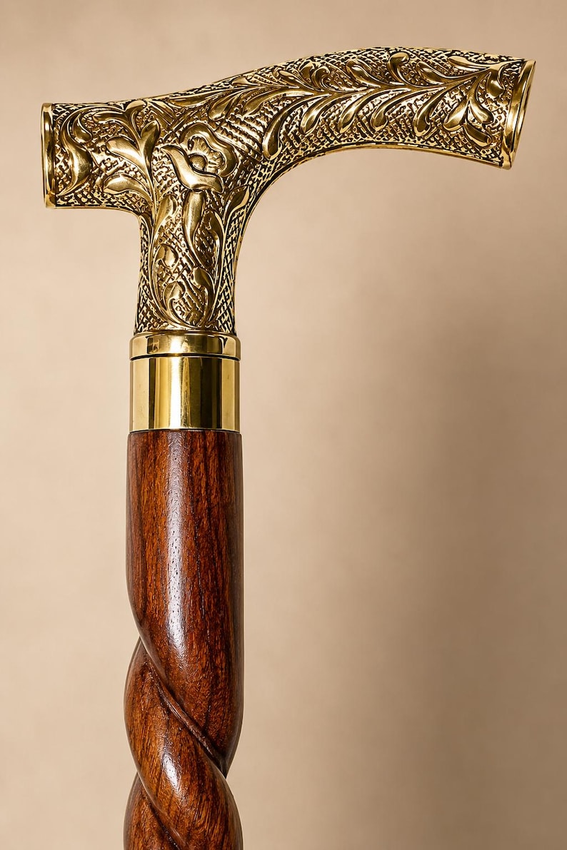 Op de afbeelding: Een wandelstok met een gepolijst, T-vormig handvat van messing, voorzien van gedetailleerde florale en ruitvormige reli&euml;fpatronen. Het handvat is verbonden met een donkerbruine houten schacht met een opvallend spiraalvormig of gedraaid ontwerp.