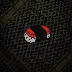 May include: A sushi-themed patch featuring a red and black design, with white accents, is set against a dark green and black houndstooth pattern. The patch is a fun, food-related accessory.