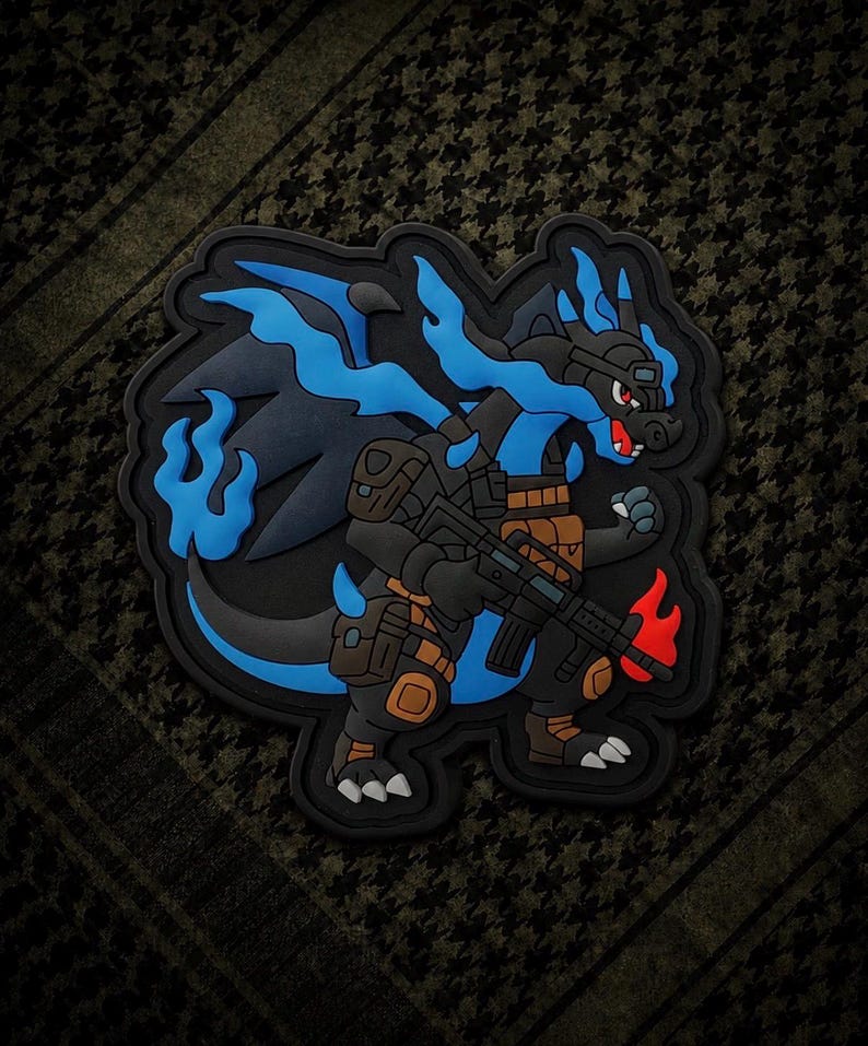 May include: A black and blue dragon patch with a military theme. The dragon is holding a rifle and has blue flames. The patch has a black border and is set against a green and black patterned background.